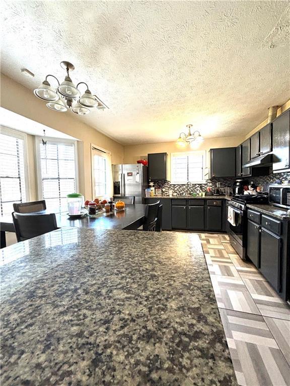 5687 Pine Meadow Ct, Morrow, GA 30260 - kitchen featuring an inviting chandelier, dark countertops, and appliances with stainless steel finishes