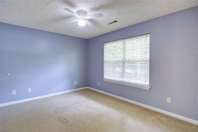 carpeted spare room with a textured ceiling, ceiling fan, visible vents, and baseboards