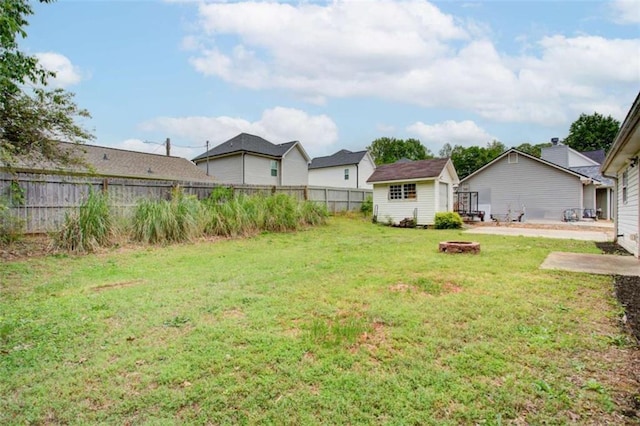 view of yard with fence, an outbuilding, and a fire pit