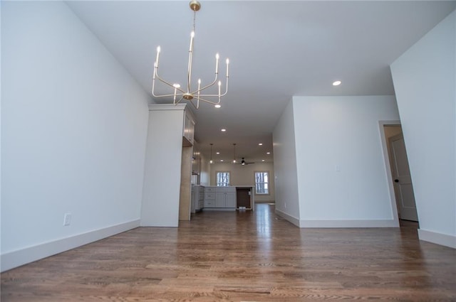 unfurnished living room featuring an inviting chandelier, baseboards, wood finished floors, and recessed lighting