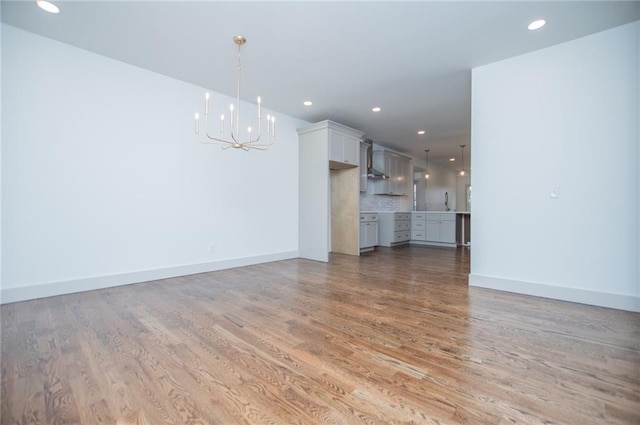 unfurnished living room with a notable chandelier, recessed lighting, baseboards, and light wood-style floors