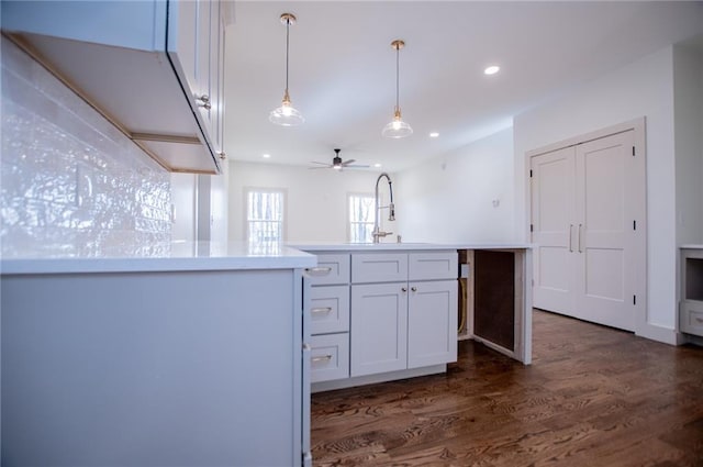 kitchen with recessed lighting, hanging light fixtures, dark wood-type flooring, white cabinetry, and a sink