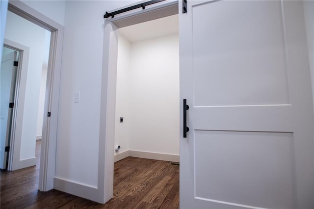 interior space with dark wood-style floors, hookup for an electric dryer, baseboards, and a barn door