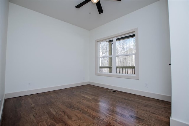 spare room featuring dark wood-type flooring, baseboards, and a ceiling fan