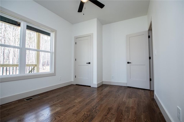 unfurnished bedroom with visible vents, dark wood finished floors, baseboards, and ceiling fan