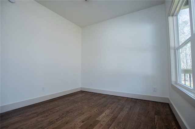 empty room featuring dark wood-type flooring and baseboards