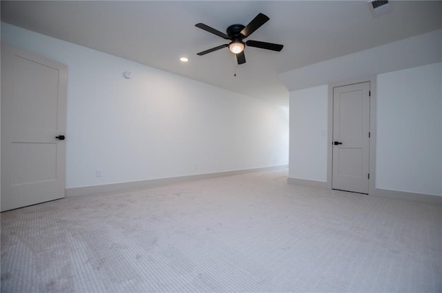 spare room featuring light carpet, a ceiling fan, visible vents, and baseboards