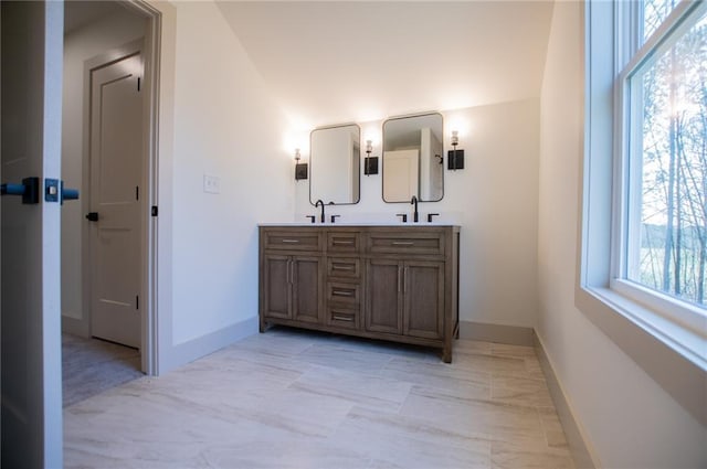 bathroom featuring a sink, baseboards, and double vanity