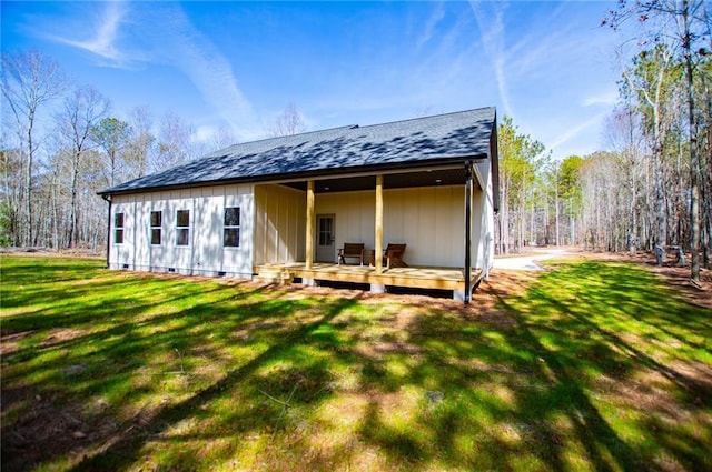 rear view of property with crawl space, a shingled roof, and a lawn