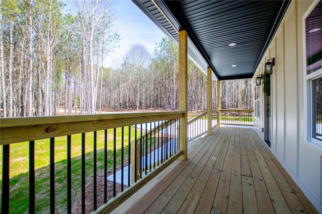 wooden terrace with a forest view and a lawn