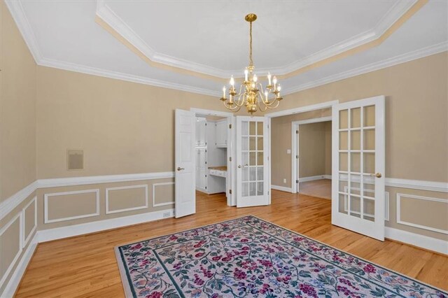 dining space featuring ornamental molding, french doors, wood-type flooring, and a notable chandelier