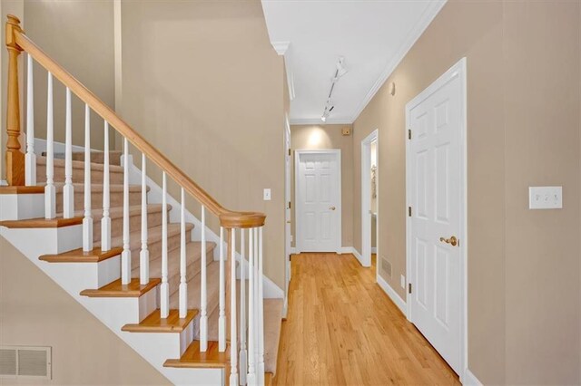 foyer entrance featuring light wood-type flooring, ornamental molding, and track lighting