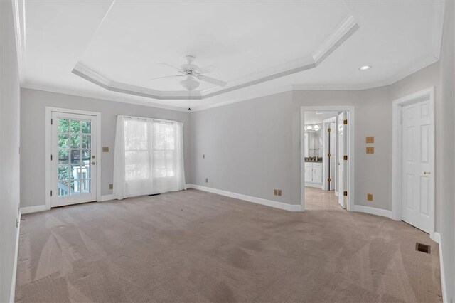 carpeted empty room featuring a tray ceiling, ceiling fan, and crown molding