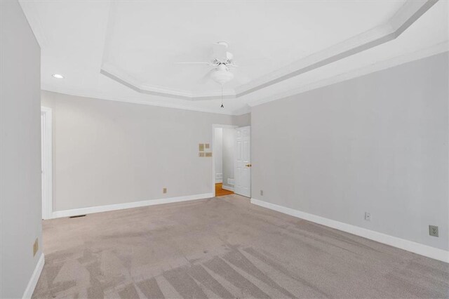 unfurnished room featuring ceiling fan, a raised ceiling, ornamental molding, and light carpet