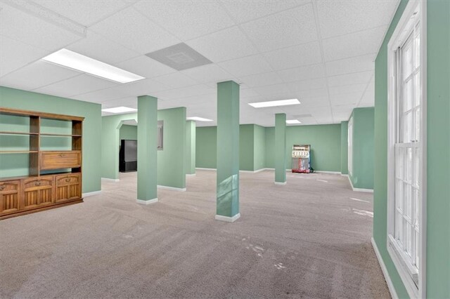 basement featuring a drop ceiling and light colored carpet