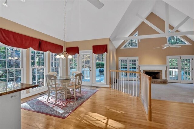 dining room with ceiling fan with notable chandelier, light hardwood / wood-style flooring, high vaulted ceiling, and french doors