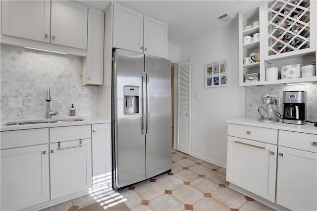 kitchen featuring tasteful backsplash, stainless steel fridge, open shelves, and a sink