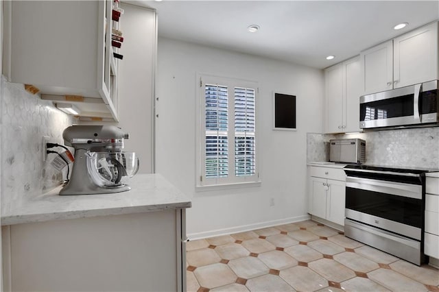 kitchen with light stone countertops, recessed lighting, stainless steel appliances, white cabinets, and tasteful backsplash