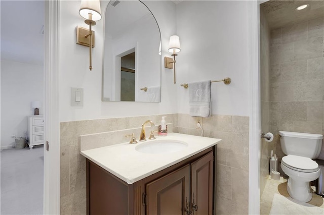 bathroom featuring toilet, tile walls, and vanity