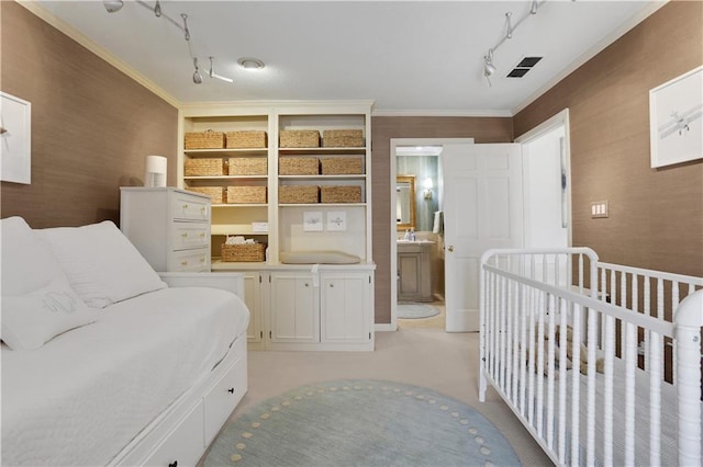 bedroom with visible vents, a nursery area, ornamental molding, and track lighting