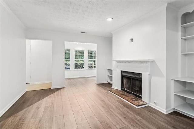 1931 Brian Way, Decatur, GA 30033 - unfurnished living room with wood finished floors, a fireplace with raised hearth, baseboards, built in features, and a textured ceiling