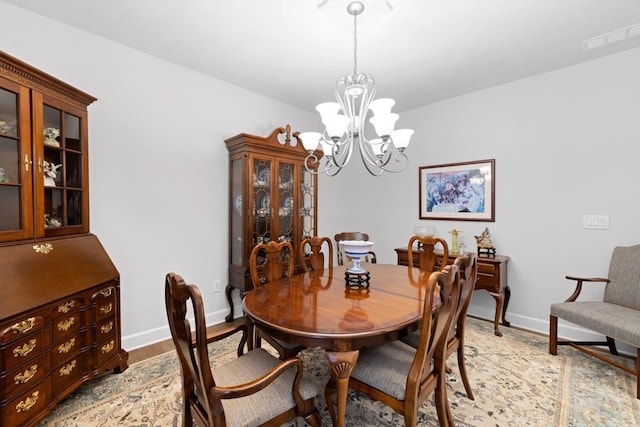 dining area with visible vents, baseboards, light wood-style floors, and an inviting chandelier