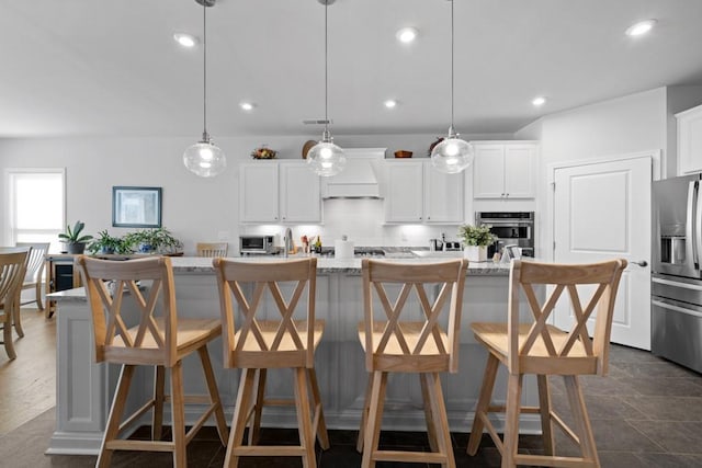 kitchen with recessed lighting, appliances with stainless steel finishes, white cabinetry, and a kitchen island with sink