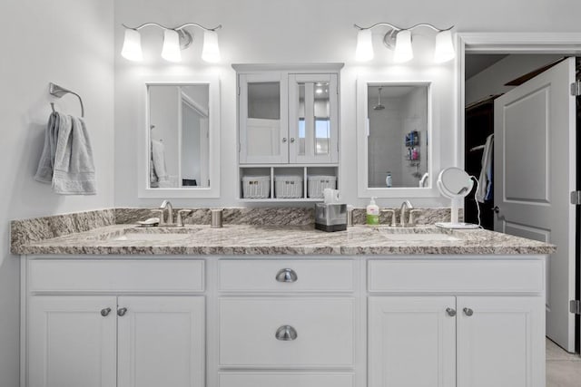 full bathroom featuring double vanity, tiled shower, and a sink