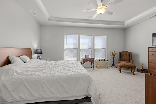 carpeted bedroom featuring visible vents, baseboards, a raised ceiling, and ceiling fan