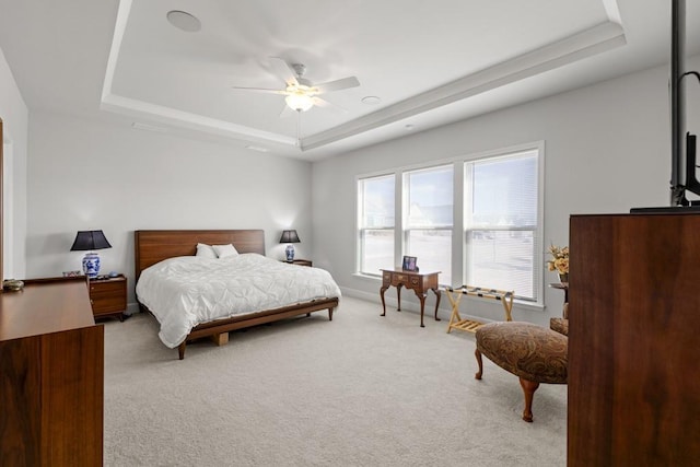 bedroom featuring a tray ceiling, baseboards, light colored carpet, and a ceiling fan