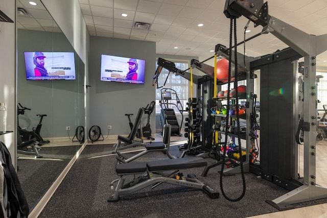 exercise room featuring a paneled ceiling, visible vents, and baseboards