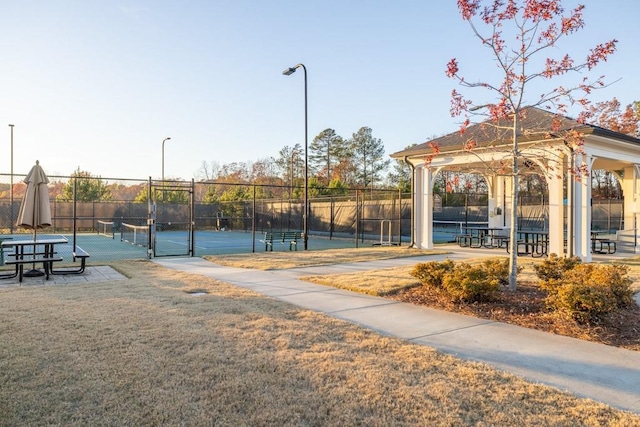 view of community featuring a tennis court, fence, a gazebo, a yard, and a gate