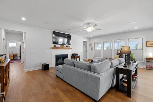 living room with recessed lighting, a fireplace, baseboards, and wood finished floors