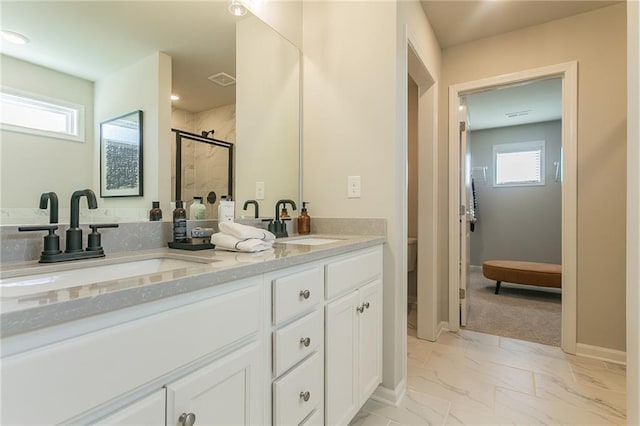 full bath featuring a stall shower, marble finish floor, a sink, and double vanity