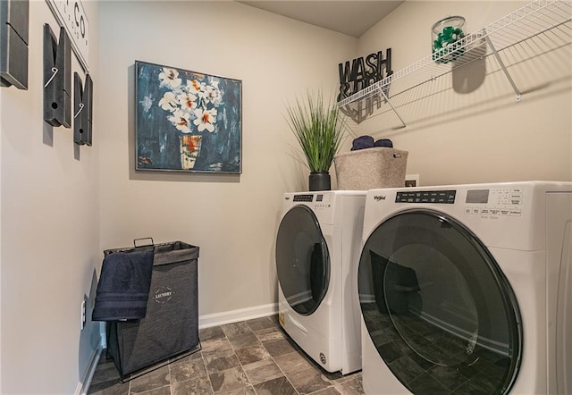 laundry room featuring washer and dryer, laundry area, stone finish floor, and baseboards