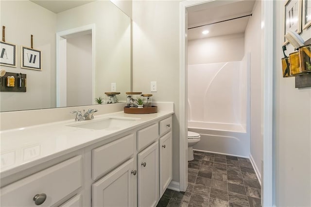 bathroom with shower / tub combination, toilet, vanity, baseboards, and stone finish flooring