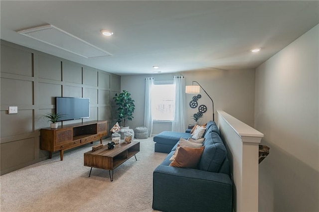 living area featuring light carpet, attic access, and a decorative wall