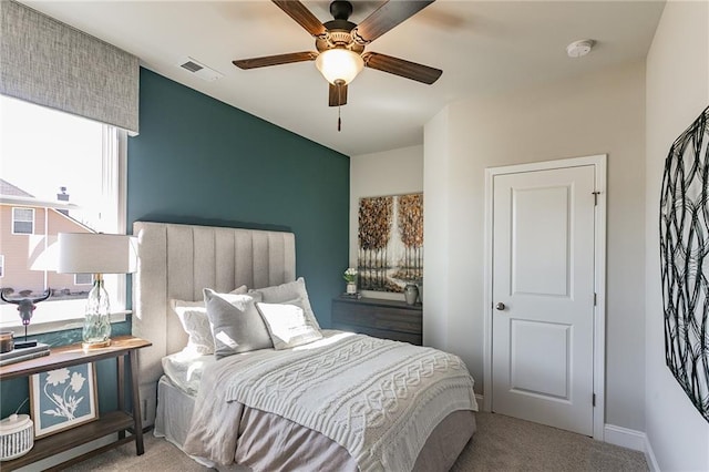 carpeted bedroom featuring a ceiling fan, visible vents, and baseboards