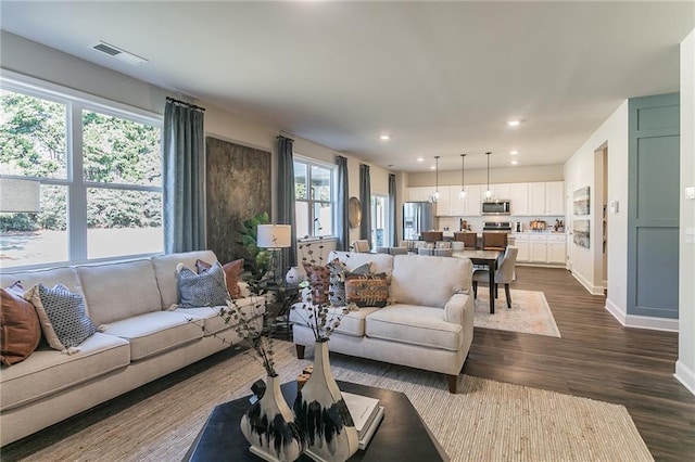 living room featuring recessed lighting, dark wood-style flooring, visible vents, and baseboards