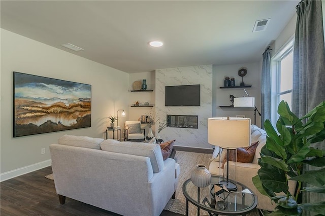 living room featuring baseboards, visible vents, dark wood-type flooring, and a high end fireplace