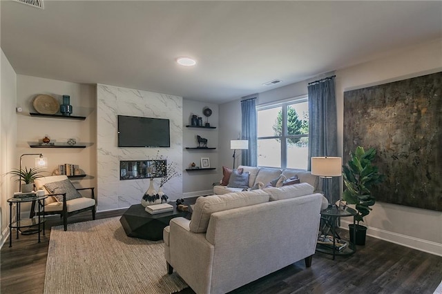 living area featuring dark wood-type flooring, a high end fireplace, visible vents, and baseboards