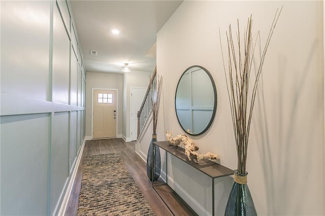 doorway with stairs, dark wood finished floors, and baseboards