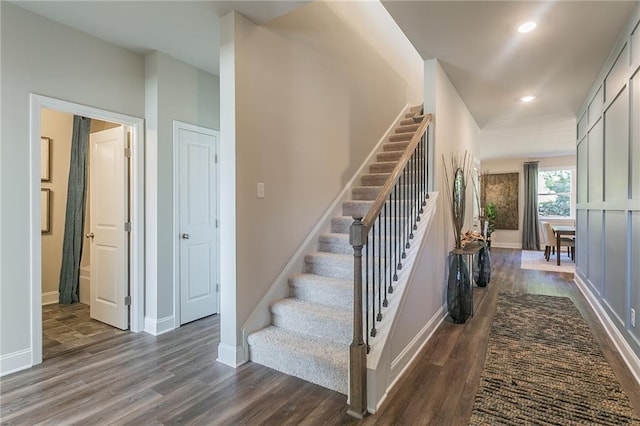 stairs with baseboards, wood finished floors, and recessed lighting