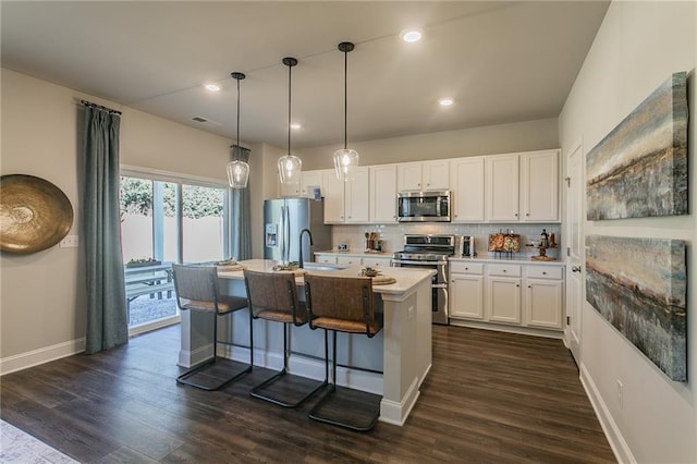 kitchen with stainless steel appliances, dark wood-style flooring, white cabinets, backsplash, and a center island with sink