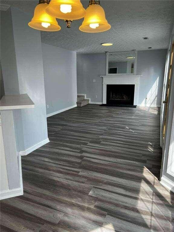 unfurnished living room featuring dark wood-type flooring and a textured ceiling