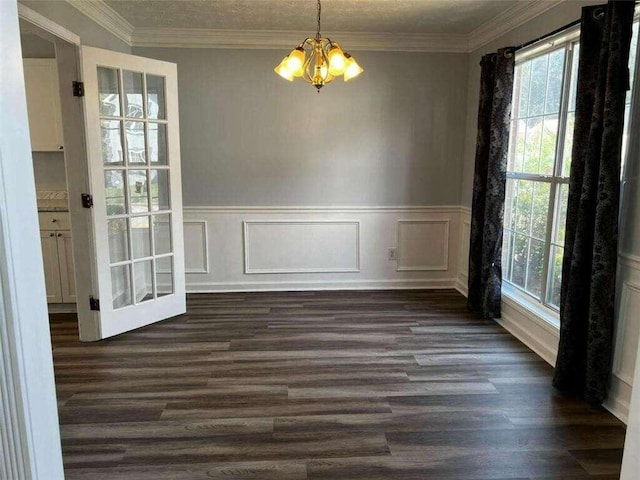 unfurnished dining area with crown molding, an inviting chandelier, and dark hardwood / wood-style flooring