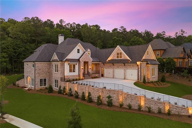 view of front of house with an attached garage, a standing seam roof, metal roof, fence, and a front lawn