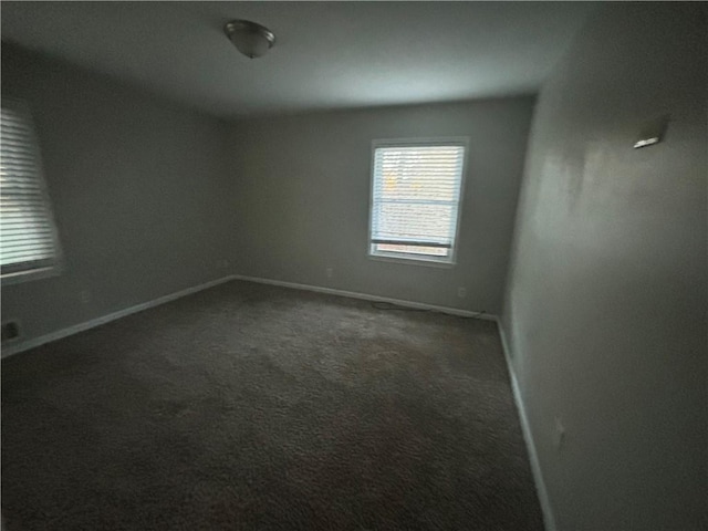 unfurnished room featuring dark carpet