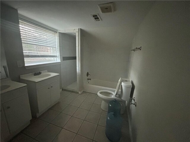 bathroom with tile patterned floors, vanity, vaulted ceiling, tiled shower, and toilet