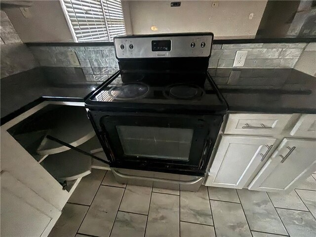 kitchen featuring tile patterned floors, white cabinetry, backsplash, and black range with electric cooktop